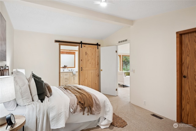 bedroom featuring connected bathroom, light carpet, a barn door, and vaulted ceiling with beams