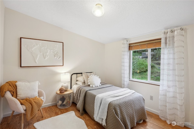 bedroom with a textured ceiling, hardwood / wood-style flooring, and vaulted ceiling