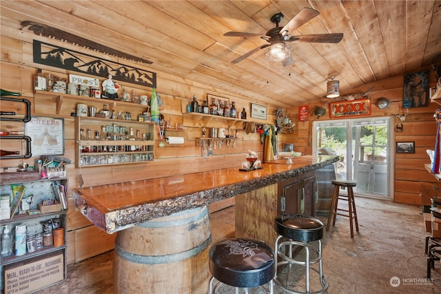 bar featuring wood walls, vaulted ceiling, ceiling fan, and wooden ceiling