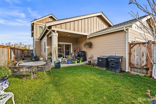 rear view of property featuring cooling unit, a lawn, and a patio area