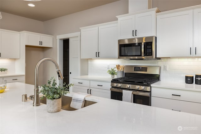 kitchen with white cabinets, decorative backsplash, sink, and appliances with stainless steel finishes