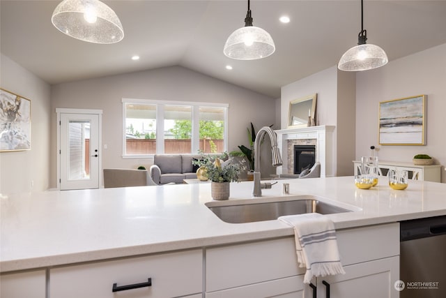 kitchen featuring stainless steel dishwasher, white cabinets, lofted ceiling, and hanging light fixtures