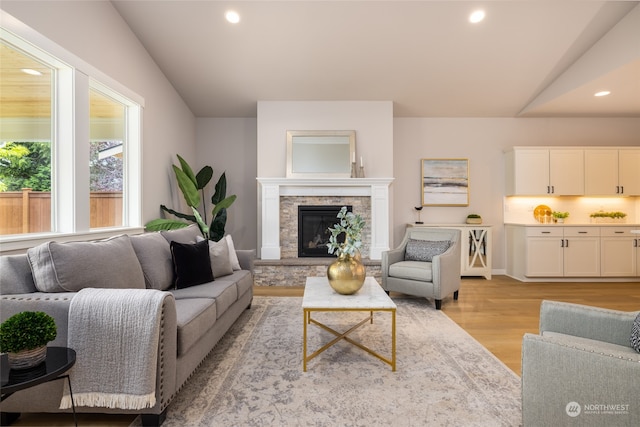 living room with a fireplace, light wood-type flooring, and vaulted ceiling