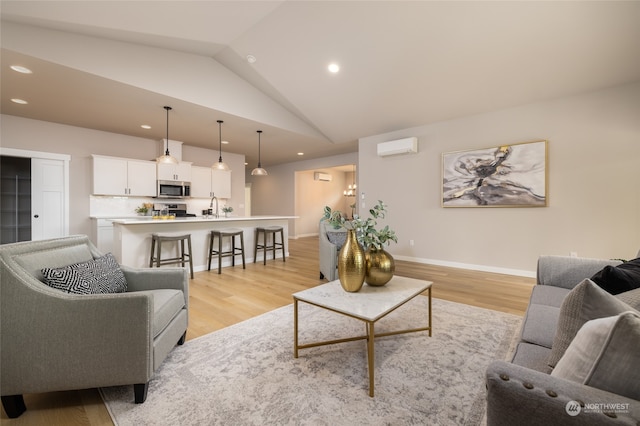 living room with lofted ceiling, a wall unit AC, and light hardwood / wood-style flooring