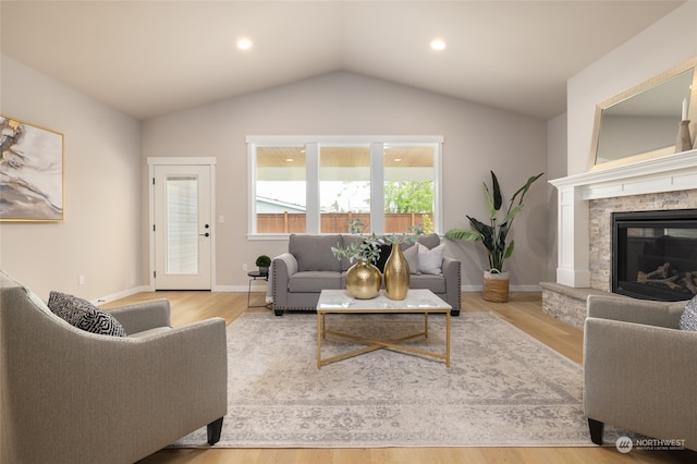 living room featuring a fireplace, lofted ceiling, and light wood-type flooring