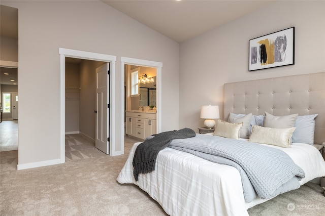 bedroom featuring ensuite bath, light colored carpet, a spacious closet, a closet, and lofted ceiling