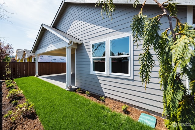 view of side of property featuring a patio and a lawn