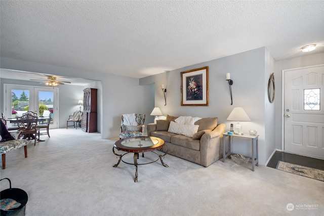 carpeted living room with ceiling fan and a textured ceiling