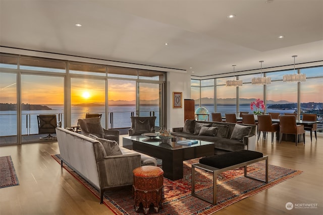 living room with a water view, plenty of natural light, expansive windows, and light hardwood / wood-style flooring