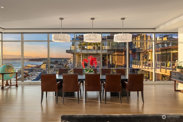 dining room featuring a water view, wood-type flooring, a wall of windows, and an inviting chandelier