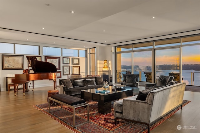 living room featuring a water view, hardwood / wood-style flooring, and floor to ceiling windows