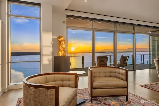 living area with a water view, plenty of natural light, and hardwood / wood-style floors