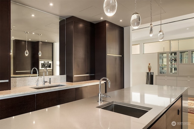 kitchen with light stone countertops, hanging light fixtures, and sink