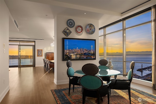 dining room with a water view, a wall of windows, and hardwood / wood-style floors