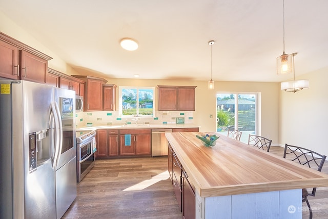 kitchen with a kitchen island, decorative backsplash, hanging light fixtures, and stainless steel appliances