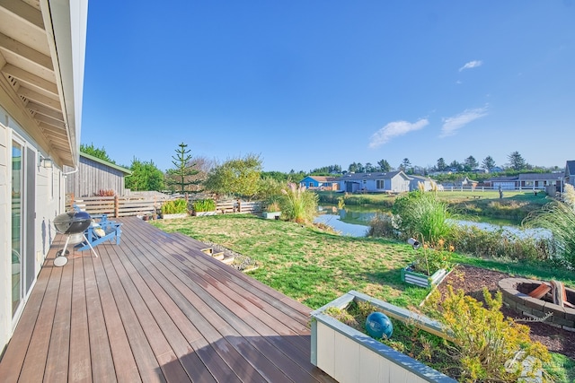 wooden deck with a water view and a lawn