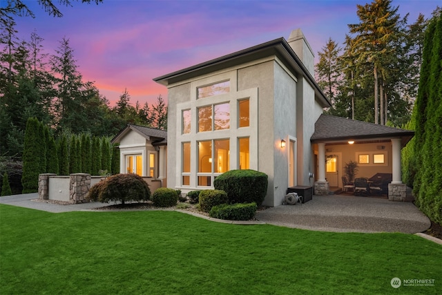 back house at dusk with a yard and a patio area