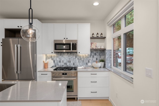 kitchen with high quality appliances, white cabinets, and decorative light fixtures