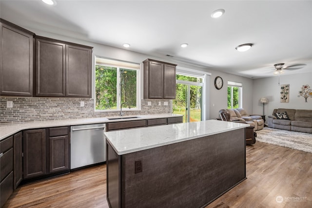 kitchen featuring a kitchen island, decorative backsplash, stainless steel dishwasher, sink, and light hardwood / wood-style flooring