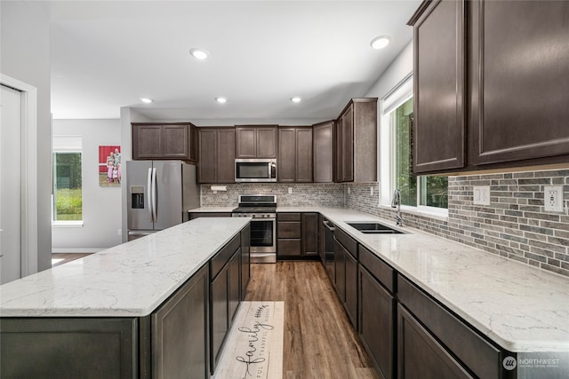 kitchen with tasteful backsplash, dark brown cabinetry, sink, appliances with stainless steel finishes, and hardwood / wood-style flooring