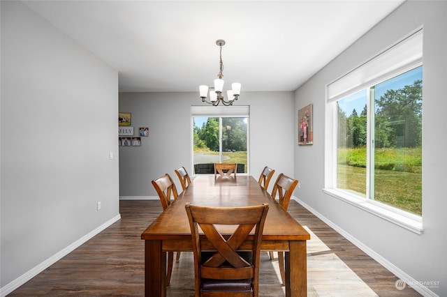 dining space featuring dark wood-type flooring, a notable chandelier, and a wealth of natural light