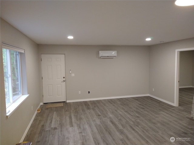 interior space with wood-type flooring and a wall unit AC