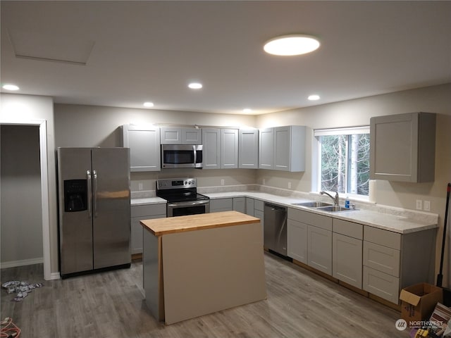 kitchen featuring sink, wood counters, light hardwood / wood-style flooring, appliances with stainless steel finishes, and gray cabinets