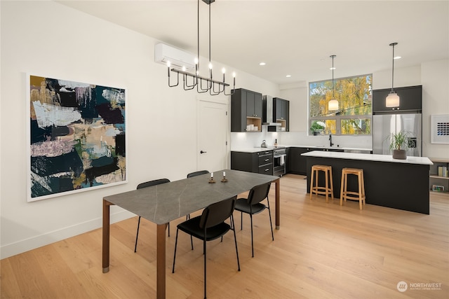 dining area featuring an inviting chandelier, light wood-type flooring, and sink