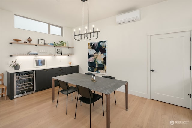 dining area featuring a notable chandelier, wine cooler, a wall mounted AC, and light hardwood / wood-style flooring