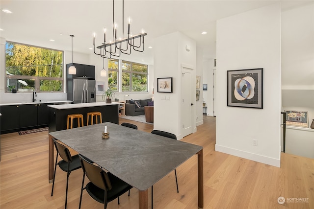 dining room featuring light wood-type flooring, sink, and a chandelier