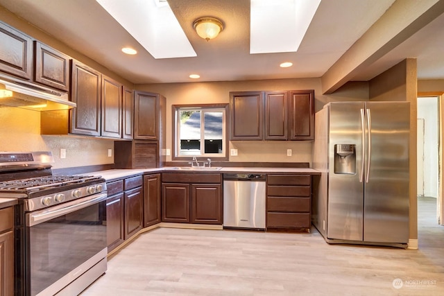 kitchen featuring light hardwood / wood-style floors, a skylight, appliances with stainless steel finishes, and sink