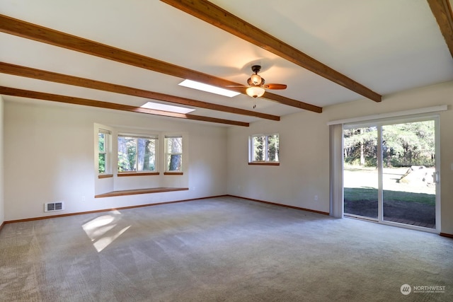 carpeted spare room featuring a skylight, ceiling fan, and beam ceiling