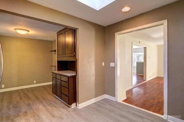 hall with a skylight and light hardwood / wood-style flooring