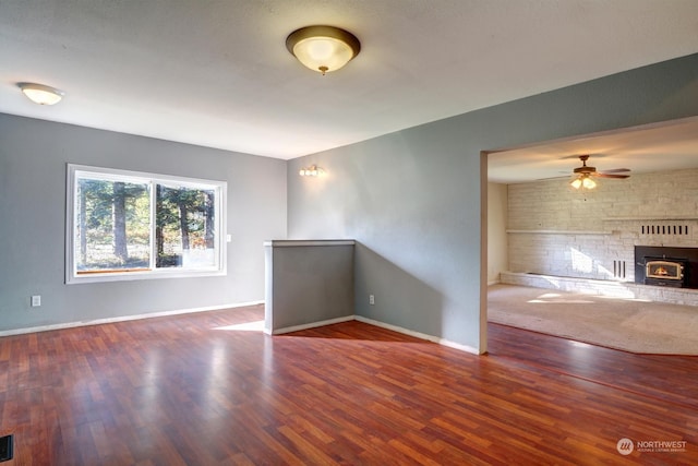 spare room with ceiling fan, dark hardwood / wood-style floors, and a wood stove