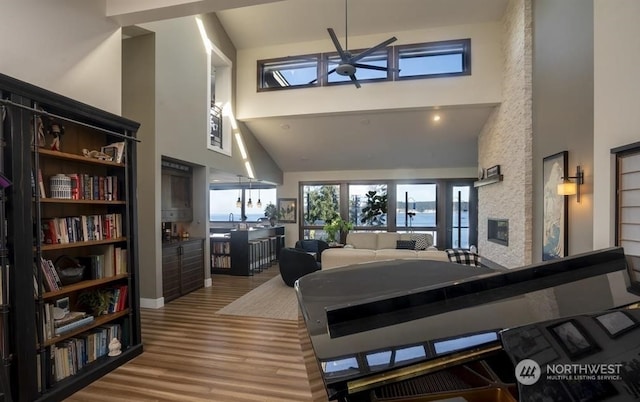 bedroom with wood-type flooring, a water view, a fireplace, and high vaulted ceiling