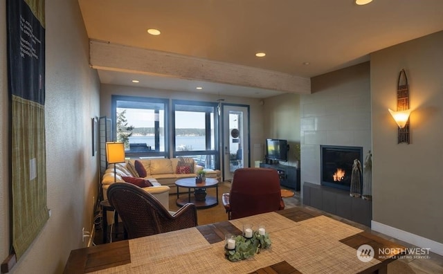 living room with beam ceiling and a tiled fireplace