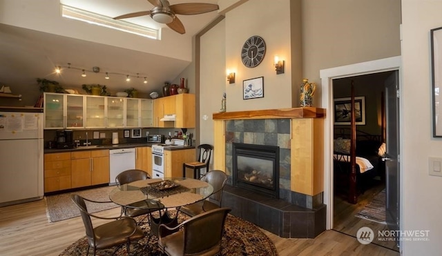 kitchen featuring ceiling fan, high vaulted ceiling, a fireplace, and white appliances