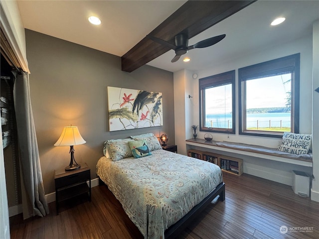 bedroom featuring ceiling fan, beam ceiling, a water view, and dark wood-type flooring