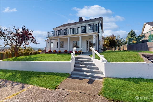 view of front of property featuring a front yard, a balcony, and covered porch