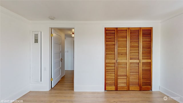 unfurnished bedroom featuring a closet, crown molding, and light hardwood / wood-style floors