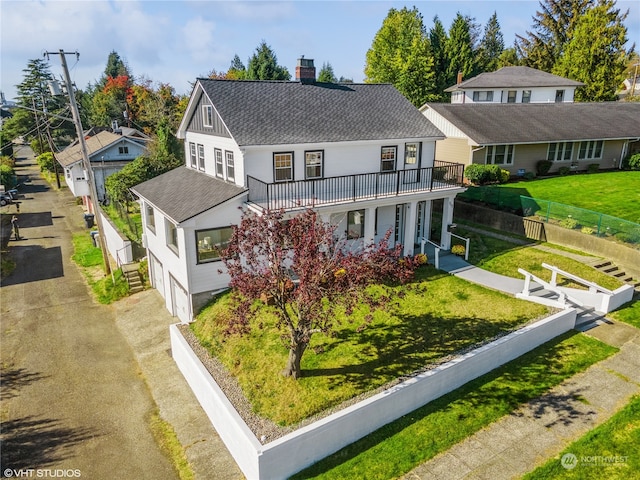 view of front of property featuring a garage, a front yard, and a balcony