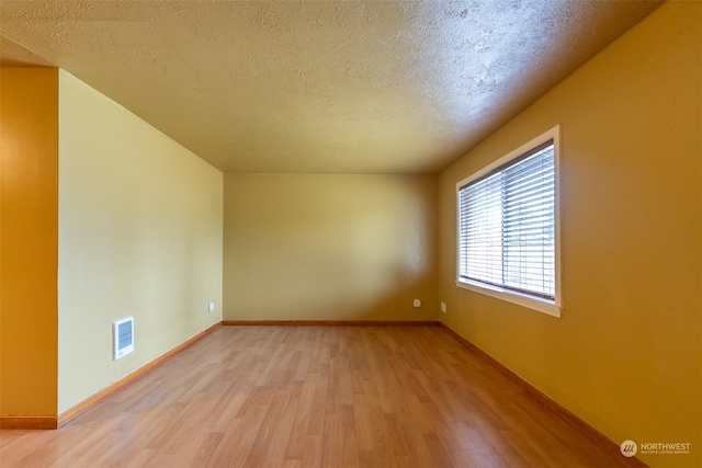 spare room featuring light hardwood / wood-style floors and a textured ceiling