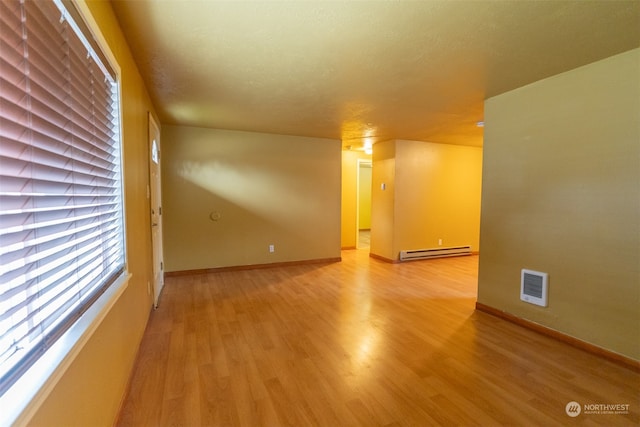 unfurnished room with a baseboard radiator, light wood-type flooring, and a textured ceiling