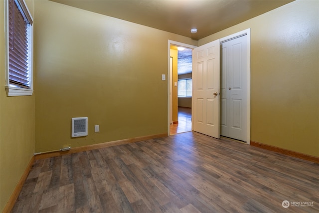 spare room with heating unit and dark hardwood / wood-style floors