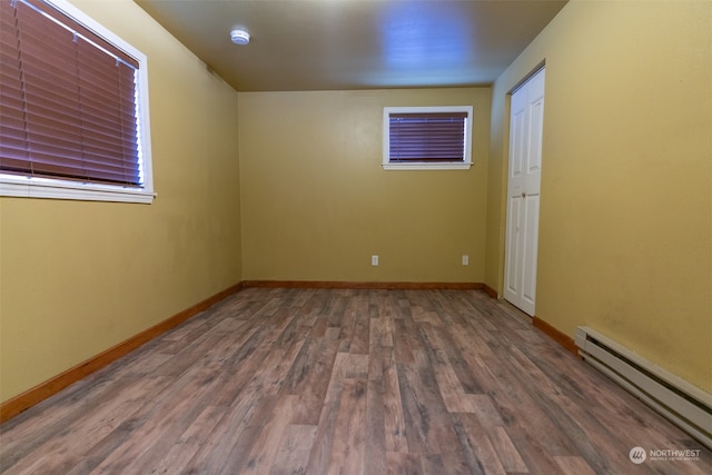 spare room with baseboard heating and dark hardwood / wood-style flooring