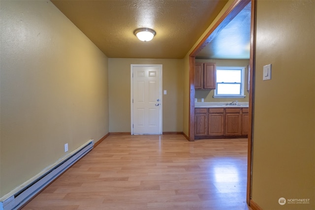 interior space featuring a textured ceiling, light hardwood / wood-style flooring, sink, and a baseboard heating unit