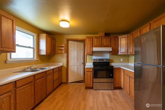 kitchen with stainless steel appliances, sink, light wood-type flooring, and a textured ceiling