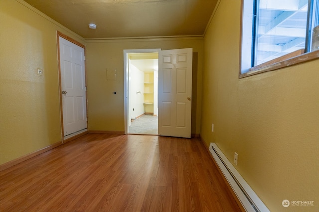 empty room with crown molding, a baseboard radiator, and light hardwood / wood-style floors