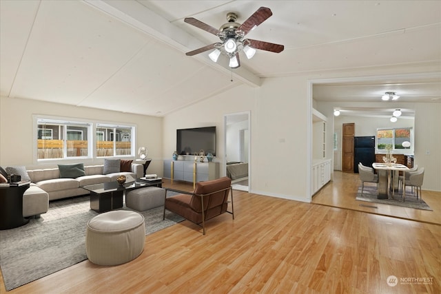 living room featuring ceiling fan, vaulted ceiling with beams, and light hardwood / wood-style floors