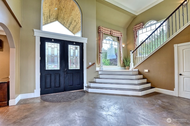 entrance foyer featuring ornamental molding, concrete flooring, and high vaulted ceiling